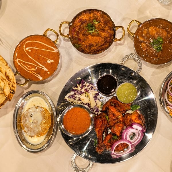 Overhead view of a table laden with various Indian dishes, including curries, naan, biryani, and tandoori chicken.
